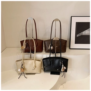 Four large tote bags in neutral colors displayed on racks with baseball charms