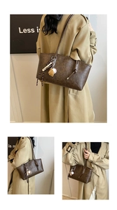 Detail of a brown leather tote bag with unique baseball charm and stylish knotted strap
