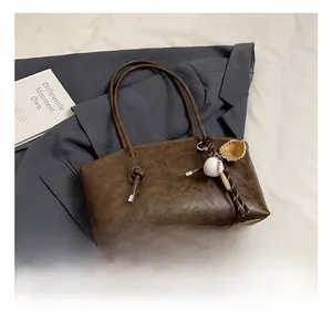 Close-up of textured dark brown PU leather tote bag with a baseball glove charm detail
