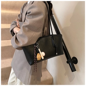 Close-up of black PU leather tote bag featuring a creative baseball-themed charm detail