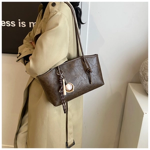 Detail of dark brown tote bag with vintage marble texture and baseball charm accessory