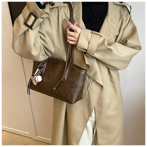 Detail of vintage brown leather tote bag featuring a creative baseball glove charm