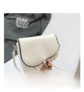 Détail du sac selle en PU blanc crème avec perles argentées et pompons métalliques