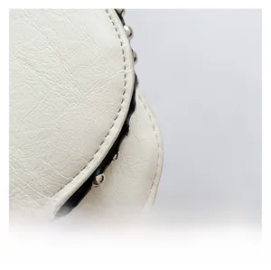 Détail du cuir grainé blanc avec des rivets métalliques et une bordure noire chic