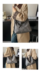 Detail view of large gray denim tote bag with vintage leather straps and metal hardware