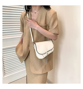 Détail du sac besace blanc avec clous argentés et glands métalliques sur un mannequin