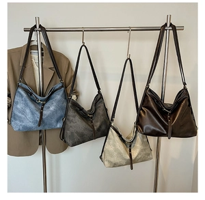 Detail view of large hobo tote bags in four vintage colors hanging on a metal rack
