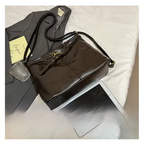 Detail of dark brown tote bag with metal buckles and straps next to a gray blazer