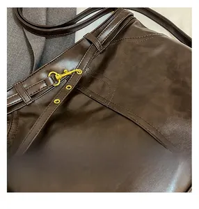 Detail of dark brown leather tote bag with gold lobster clasp and fine stitching