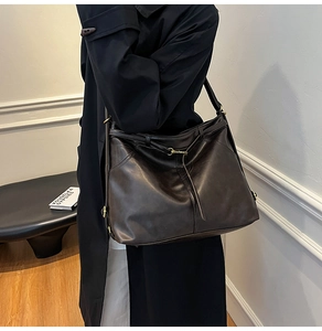 Detailed macro view of vintage oil-wax leather texture and metal strap buckle on tote bag