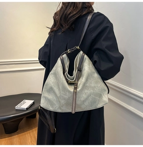 Detail of grey-green tote bag with bronze buckle and vintage aesthetic on a shoulder