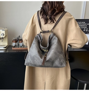 Detail eines Vintage-Rucksacks in Grau mit braunen Lederriemen in einem minimalistischen Café