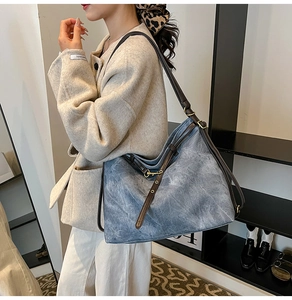 Detail of blue denim tote bag with brown leather straps and vintage metallic buckle