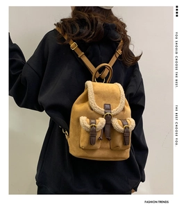 Detail view of vintage brown suede backpack with white plush trim and metallic buckles