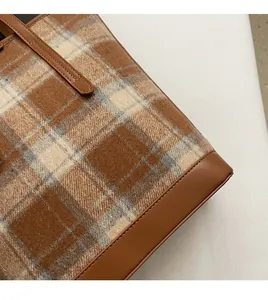 Détail du tissu en tweed à carreaux et des coutures en cuir marron du cabas