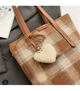 Détail du sac seau en laine à carreaux marron avec nœud en cuir et pendentif en cœur