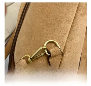 Close-up of golden metal hooks and D-ring on brown suede winter backpack details