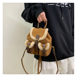 Close-up of brown suede mini backpack featuring faux shearling trim and leather buckle straps