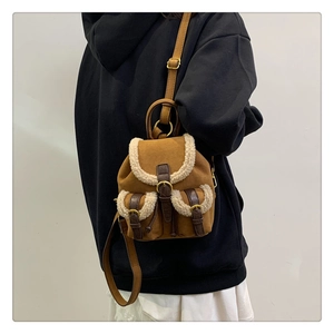 Detailed view of brown plush backpack with faux fur trim and leather straps on model
