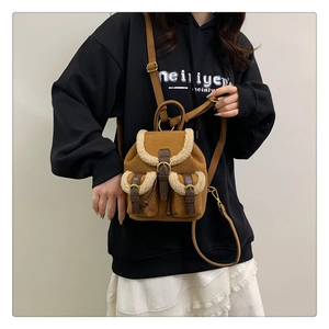 Detail of brown plush mini backpack with beige fleece trim and leather straps on model
