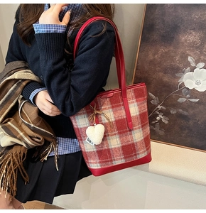 Fashionable red plaid tote bag with plush heart charm shown in a cozy autumn street style
