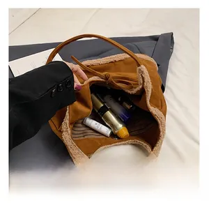 Detail shot of brown faux suede tote bag interior with striped lining and fuzzy trim
