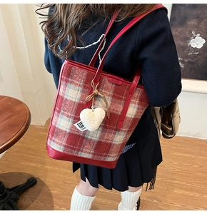 Détail du sac seau en laine à carreaux rouges avec breloque cœur en fausse fourrure