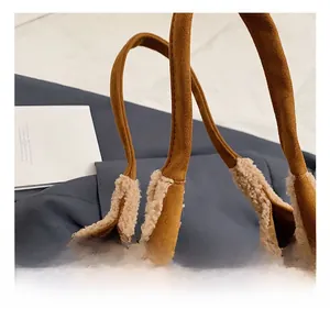 Detail of the brown suede handbag showing the soft cream sherpa trim and sturdy handle