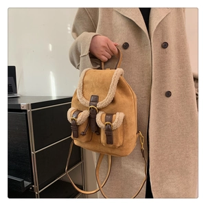 Detail of camel suede backpack with soft white fleece trim and magnetic leather buckles