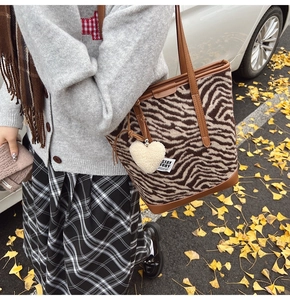 Detail of zebra pattern wool tote bag with leather handles and white heart charm