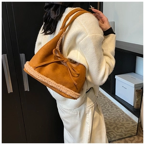 Detail of plush tote bag with suede bow worn by model for autumn winter style