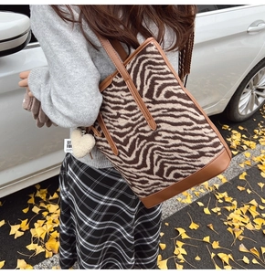 Détail du sac cabas en peluche à motif zèbre avec lanières en cuir et bijou de cœur