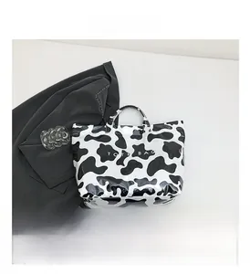 Detail view of stylish cow print PVC tote bag with TOTE BAG lettering and modern pattern