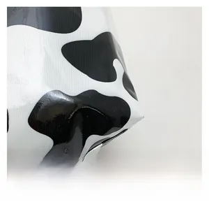 Detail view of glossy cow print fabric texture and stitching on a large tote bag