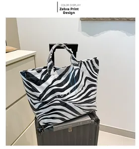 Close-up of zebra pattern tote bag with reinforced handles on a black suitcase