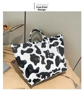 Close-up of waterproof PVC tote bag featuring black and white cow print and text logo