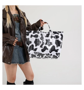 Detail of trendy cow print PVC tote bag featuring glossy finish and white TOTE BAG text
