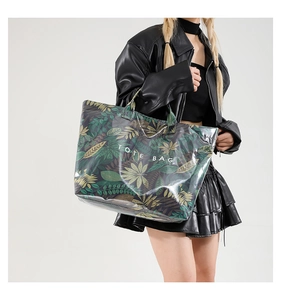 Detail of large tote bag with tropical leaf print and white TOTE BAG text on model