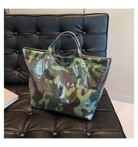Glossy green camo tote bag with white TOTE BAG text on a modern black leather chair