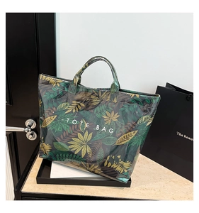 Detail of waterproof green tropical leaf print tote bag with bold white text on surface