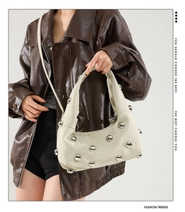 Detailed texture of cream pleated shoulder bag with silver metallic sphere studs