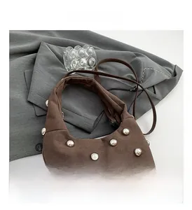 Detail of brown suede tote with silver ball studs and crossbody strap on grey blazer