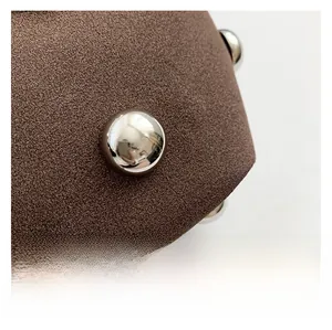 Macro view of brown suede fabric with polished silver studs on a shoulder bag