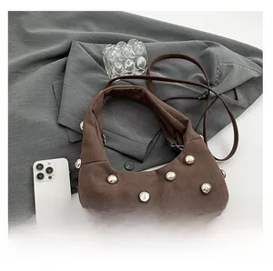 Detail of brown suede shoulder bag with oversized silver studs and leather strap