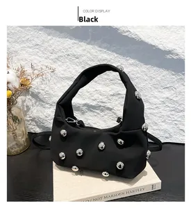 Detail of black nylon handbag featuring large silver hemispherical metal studs on the surface
