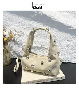 Close-up of khaki shoulder bag with silver ball studs on book and floral background