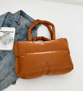 Detail view of glossy caramel quilted down tote bag with dual handles and puffy texture