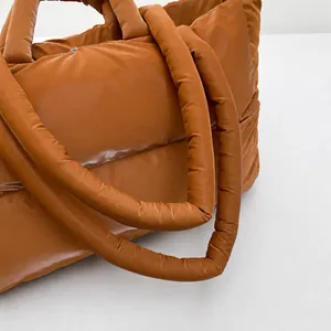 Close-up detail of the soft padded shoulder straps on a brown quilted puffer tote bag