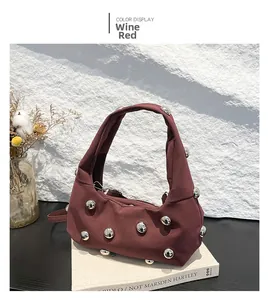 Detail view of wine red shoulder bag with silver metallic bead decor on white stone backdrop