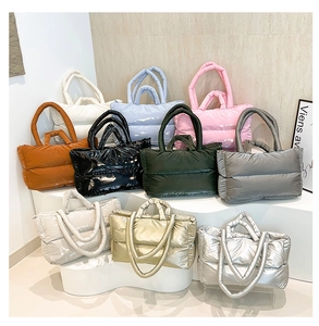Multiple colors of quilted down tote bags displayed on a stylish wave stand